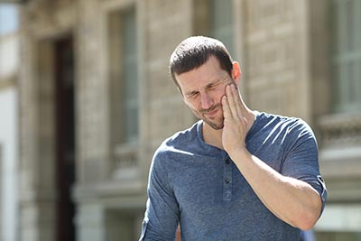 man holding his mouth from tmj pain